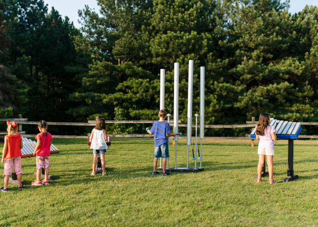 Kids playing with outdoor musical instruments at a park designed and built by Kraftsman